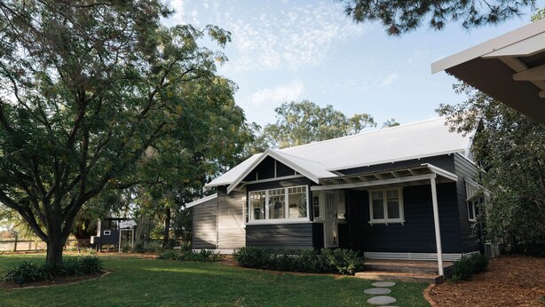 A residential house with a front porch, a lawn, and a tree. - The Foxman Cottage (Broke)