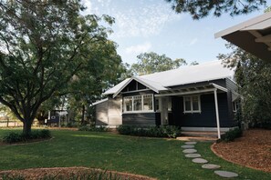 A residential house with a front porch, a lawn, and a tree. - The Foxman Cottage (Broke)