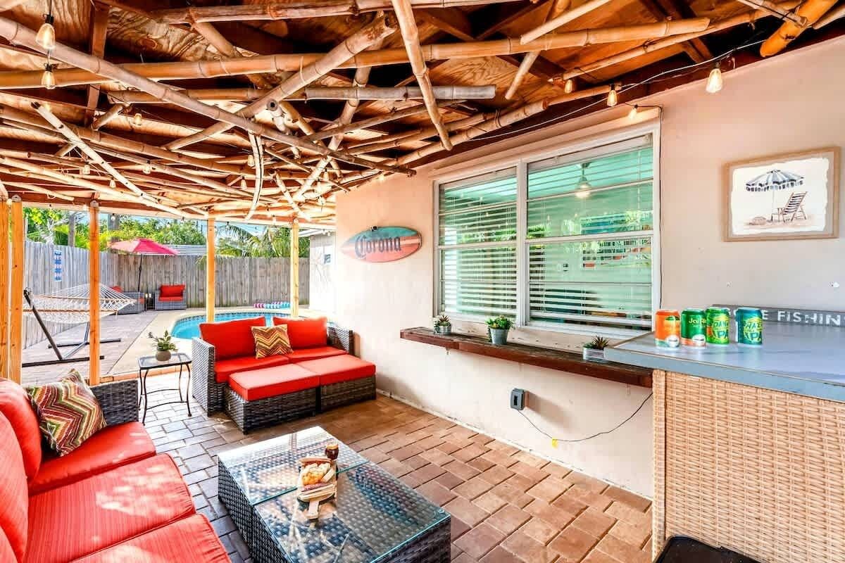 Een terras buiten met een zwembad, een bar en een groot raam.