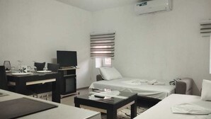Ett hotellrum med en säng, ett skrivbord, en tv och en luftkonditioneringsanläggning.