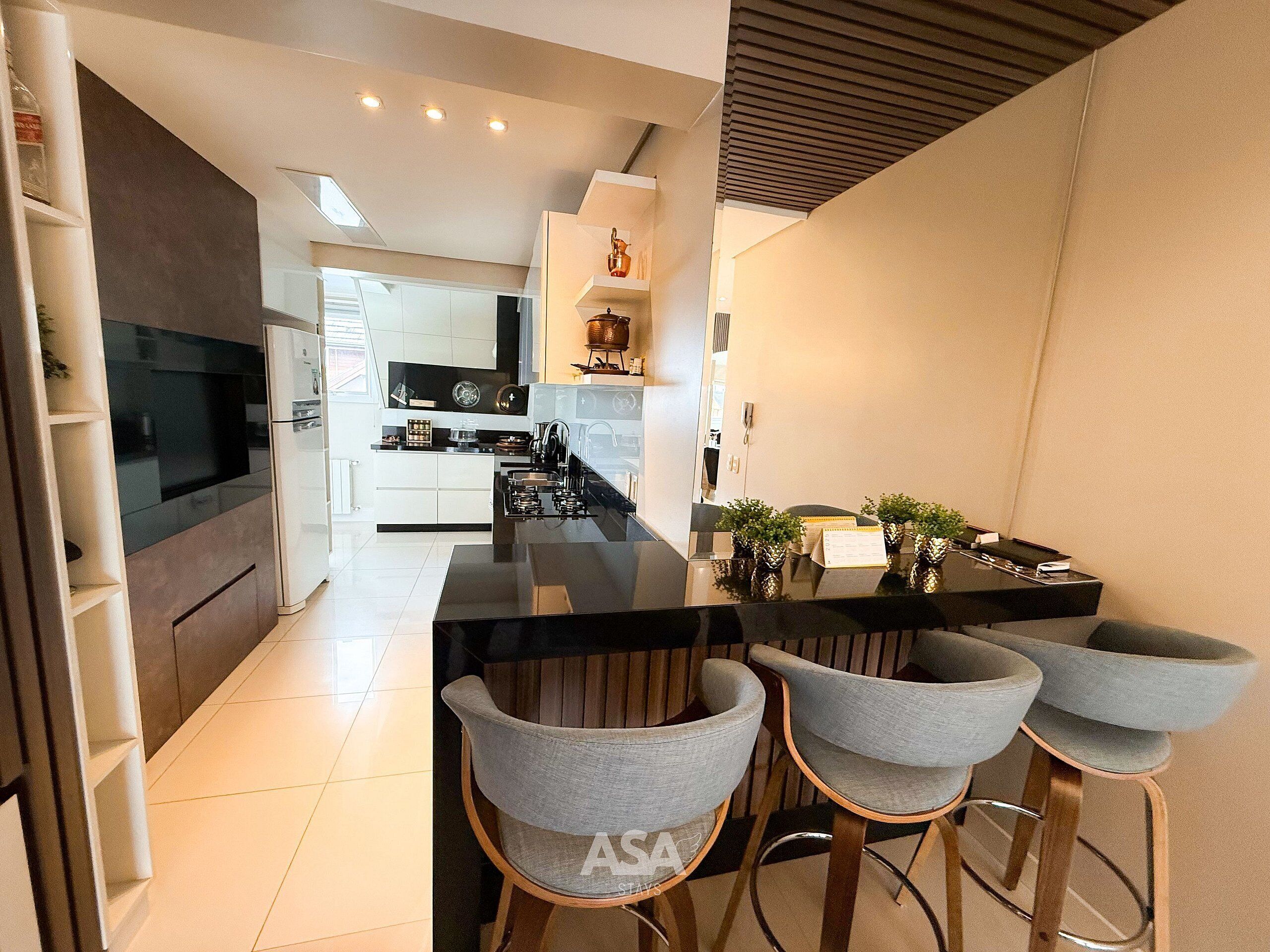 A modern kitchen with a central island, bar stools, and a built-in oven.