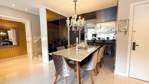 Un espace de salle à manger moderne, doté d’une grande table, de chaises et d’un lustre.