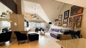 Un vaste espace de vie doté d’un haut plafond, d’une table à manger, d’un canapé et d’un fauteuil roulant.