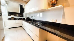 Une cuisine moderne avec des meubles blancs, un plan de travail noir et une cuisinière à gaz.