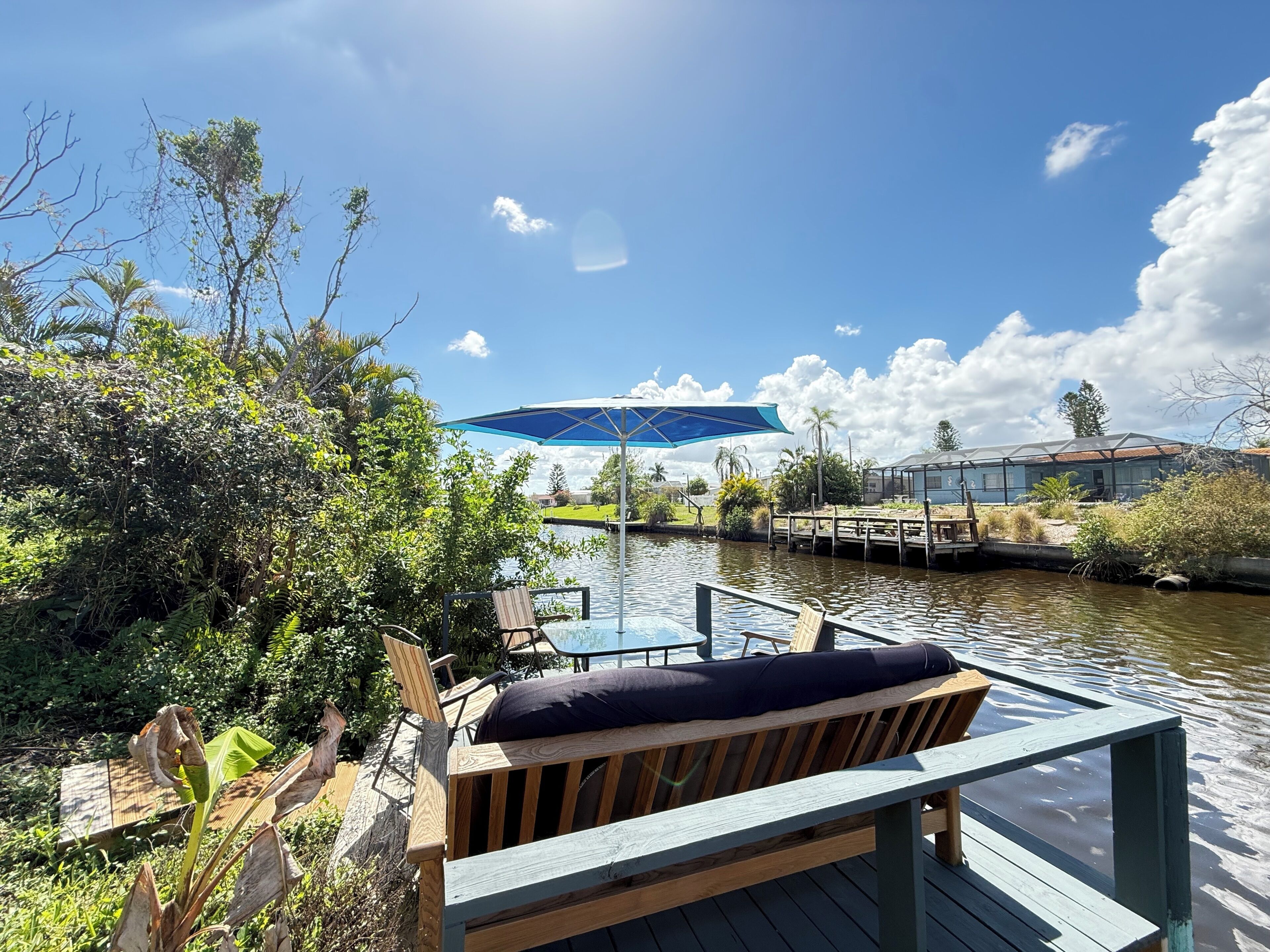 A wooden deck with a bench, a glass-enclosed structure, and a body of water.