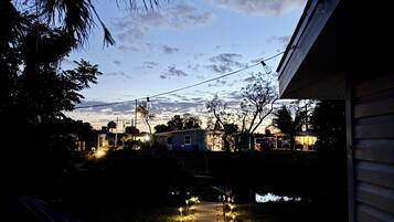 Un camino que lleva a una casa, con cielo despejado y edificios a lo lejos.