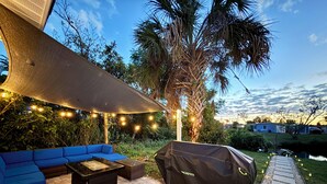 Eine Terrasse im Freien mit einer blauen Couch, einem Grill und Lichterketten.
