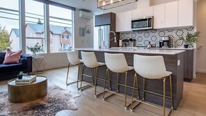 A modern kitchen with a central island, bar stools, and a large window. - Modern 3 Bedroom Townhouse w/ Private Rooftop (Seattle)