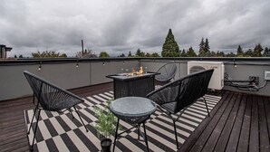 A rooftop terrace with a checkered floor, a fire pit, and outdoor furniture. - Modern 3 Bedroom Townhouse w/ Private Rooftop (Seattle)