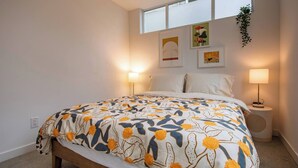 A bedroom with a bed, two bedside lamps, a window, and wall art. - Modern 3 Bedroom Townhouse w/ Private Rooftop (Seattle)