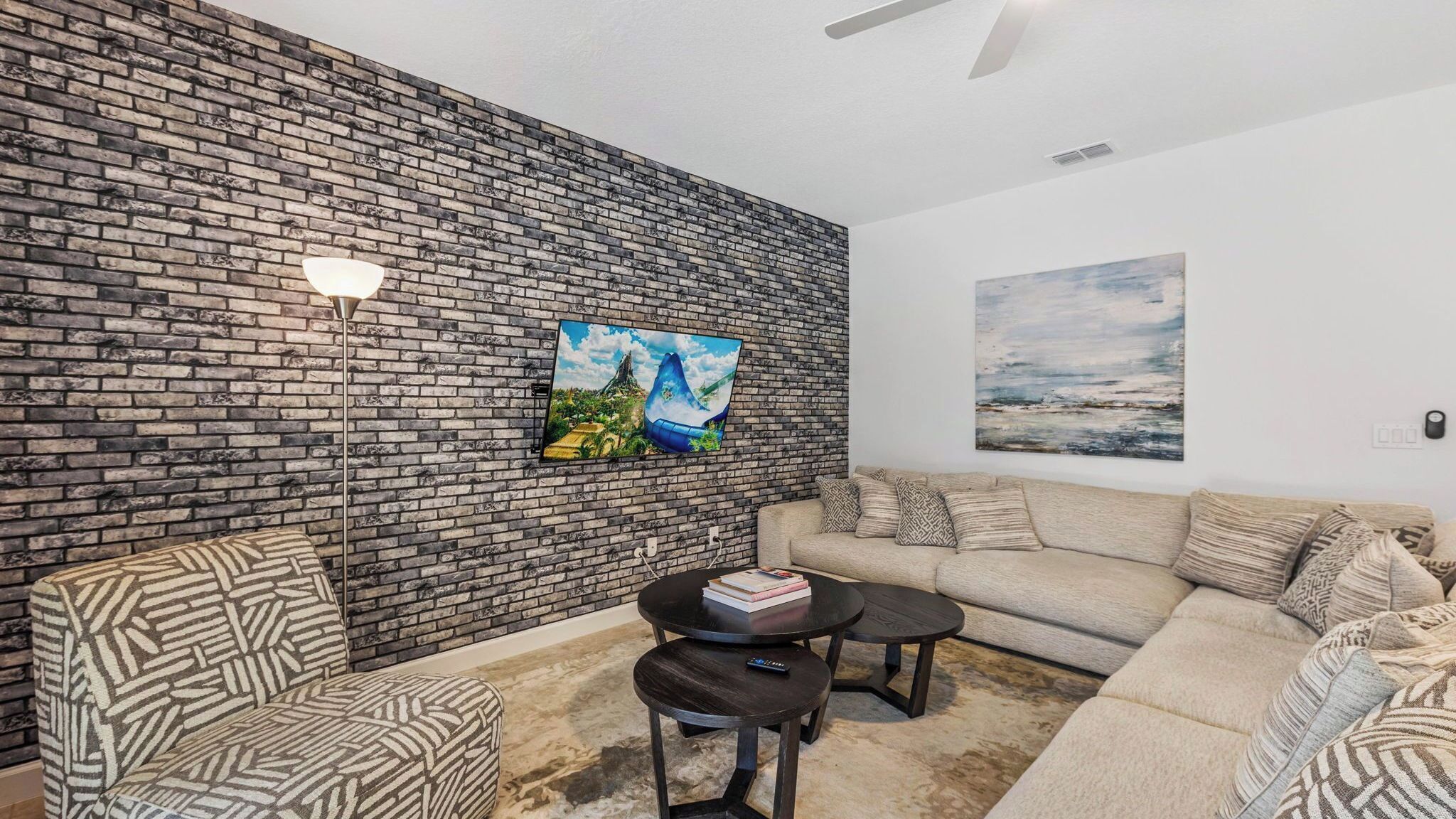 A living room with a brick wall, a sofa, a coffee table, and a floor lamp.