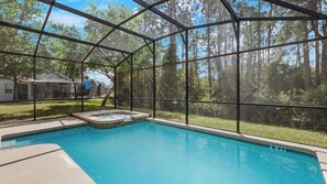 Ein Pool mit Glasüberdachung, umgeben von einem bewaldeten Gebiet.