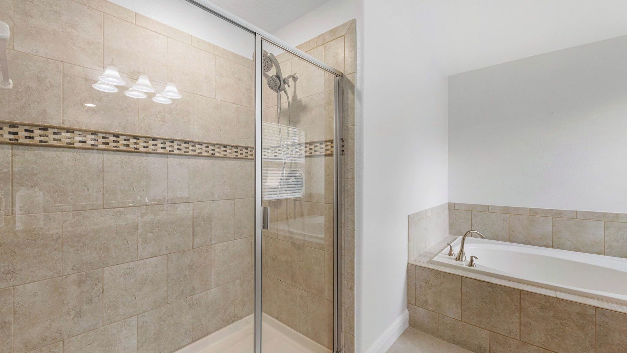 A bathroom with a glass-enclosed shower, a bathtub, and a tiled floor.