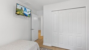A bedroom with a bed, a television mounted on the wall, and a white wardrobe. - Palm & Play by Avantstay Pool + Themed Bedrooms + Game Room Gated Resort by Disney (Kissimmee)