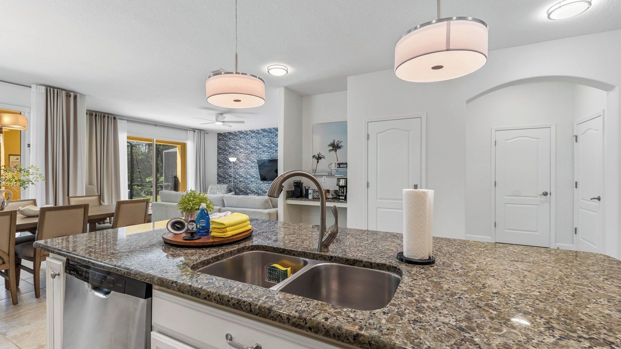 A modern kitchen with granite countertops, stainless steel appliances, and pendant lighting.