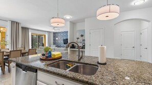 Eine moderne Küche mit Granit Arbeitsplatten, Edelstahlgeräten und Pendelleuchten.