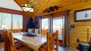 A wooden interior with a dining table and chairs, a Christmas tree, and a framed picture on the wall. - 4BR Riverfront | Hot Tub | Fireplace (South Fork)