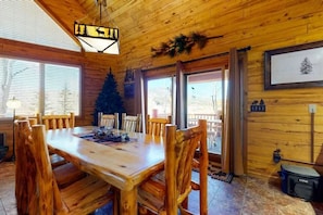 A wooden interior with a dining table and chairs, a Christmas tree, and a framed picture on the wall. - 4BR Riverfront | Hot Tub | Fireplace (South Fork)
