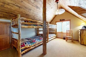 Ein rustikales Zimmer mit einem Holzbett, einem Schreibtisch und einem Stuhl.