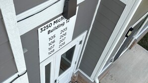 A building entrance with a sign listing building numbers and a door with a handle.