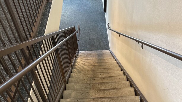 A staircase with metal railings and a handrail, leading to a landing with a door.