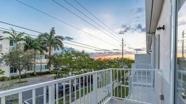 A balcony with a white railing overlooking a street with parked cars and buildings. - Peaceful Dreamscape a spacious family friendly minutes to the Keys & Miami (Princeton)