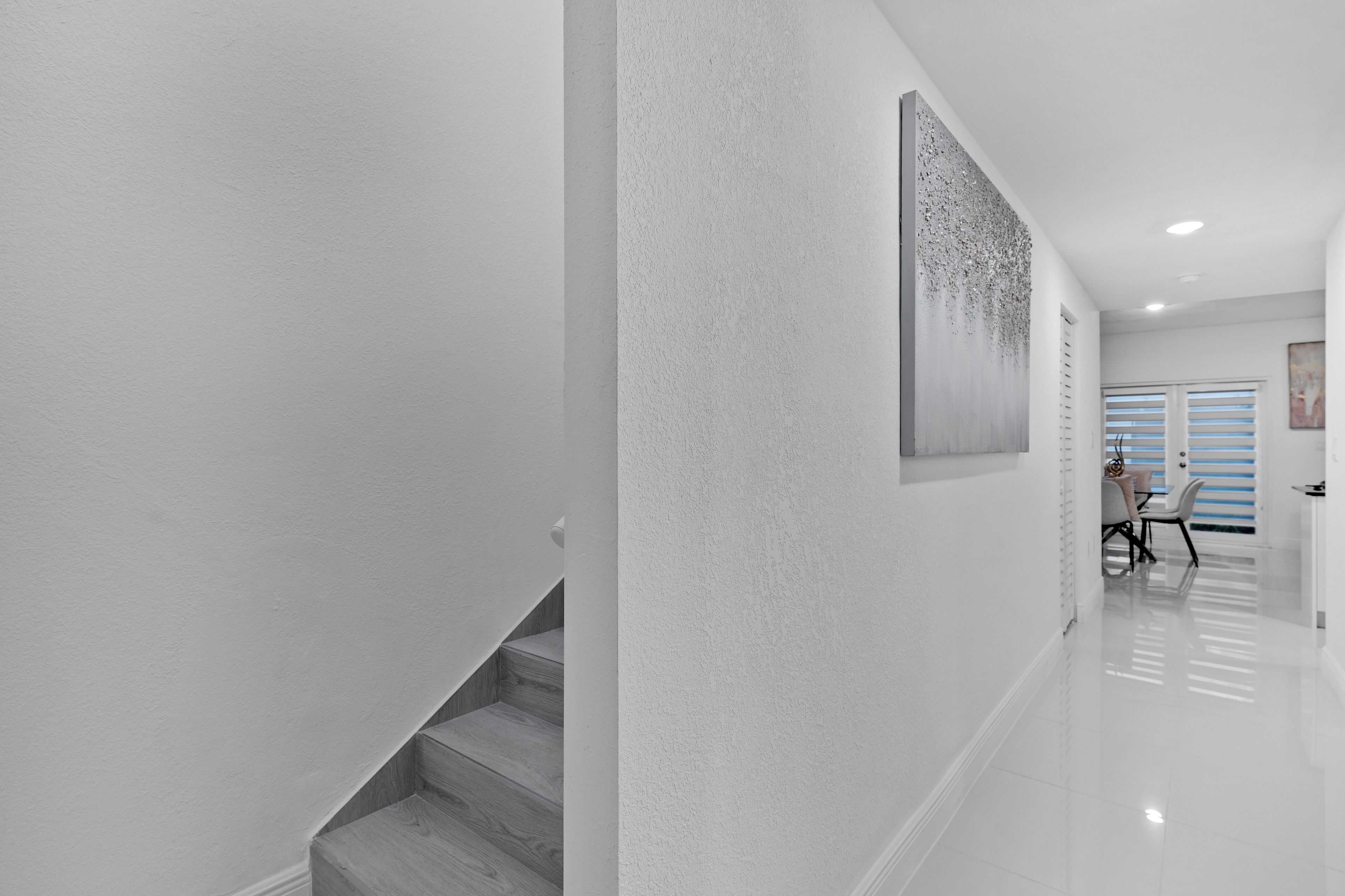 A modern interior with a staircase, a polished floor, and a painting on the wall.
