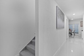 A modern interior with a staircase, a polished floor, and a painting on the wall.