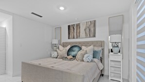 A bedroom with a large bed, a nightstand, a mirror, and a painting on the wall. - Peaceful Dreamscape a spacious family friendly minutes to the Keys & Miami (Princeton)