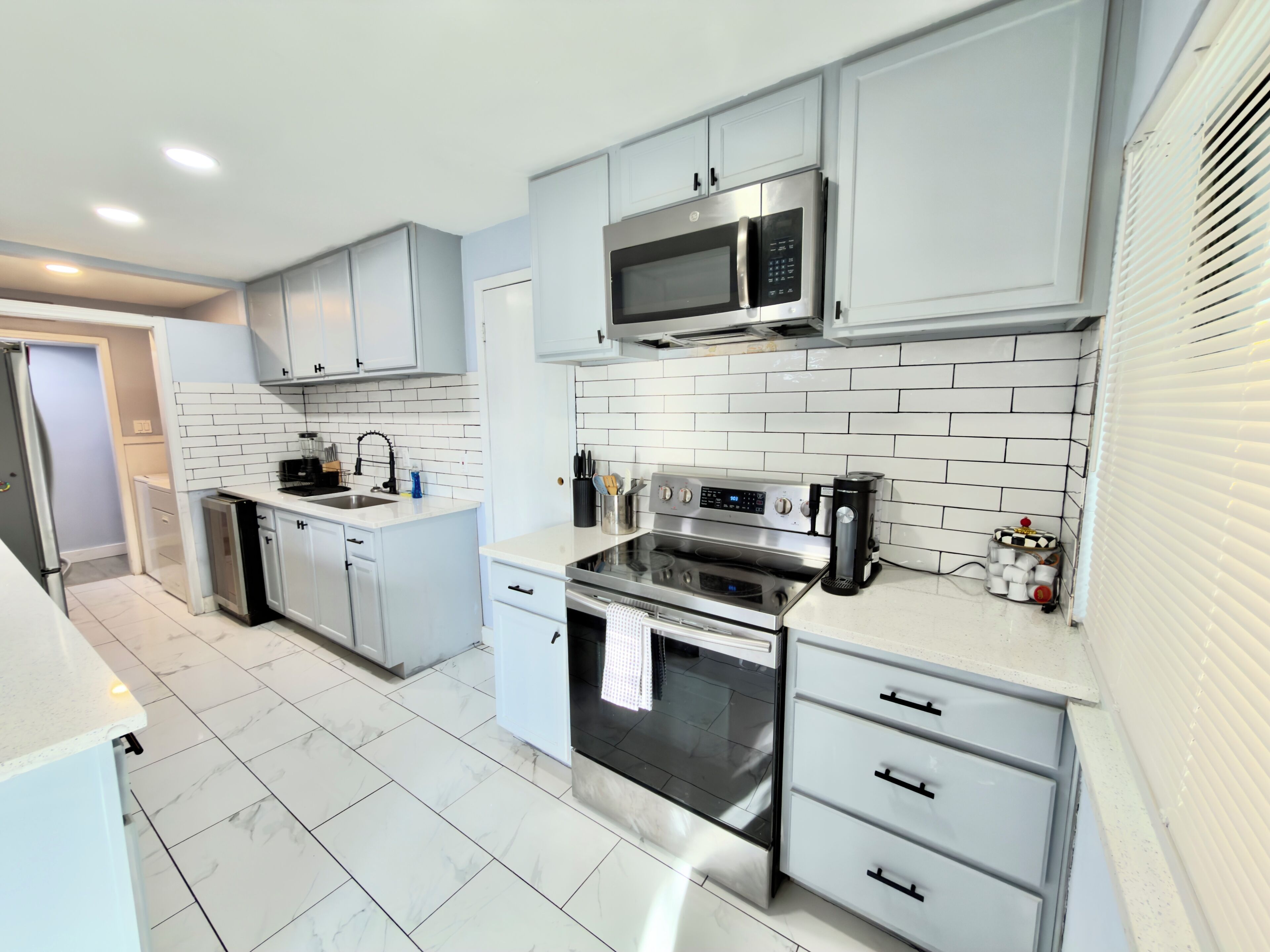 A modern kitchen with white cabinetry, a stainless steel microwave, an oven, and a dishwasher.