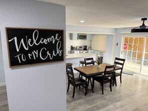 Un espace repas avec un tableau noir servant de panneau, une table en bois et des chaises.