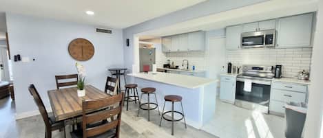 A modern kitchen with white cabinets, a stainless steel oven, and a microwave.