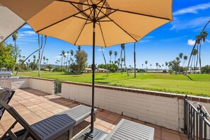 Eine Terrassengaststätte mit Blick auf einen Golfplatz, einem Grill und zwei Liegestühlen.