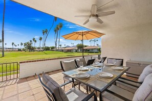 A patio with a table set for dining, overlooking a golf course.