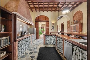 A kitchen with a stone floor, wooden cabinets, and a central island. - Grand Historic Mansion in Old SJ | Patio + Rooftop (San Juan)
