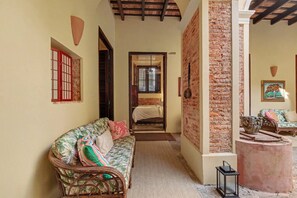 A cozy room with a sofa, a bed, and a brick wall. - Grand Historic Mansion in Old SJ | Patio + Rooftop (San Juan)