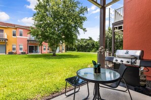 A patio with a grill, a glass table, and chairs. - Cozy 3 BD/ 2.5 BA/ Emerald Island (8403 BL) (Kissimmee)