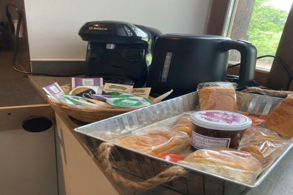 Een kitchenette met een Bosch koffiezetapparaat, een waterkoker en een mand met brood en een potje jam.