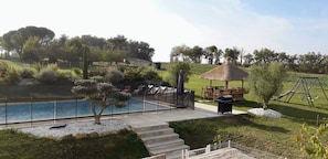 Un espace piscine doté d’un coin salon abrité, d’une balançoire et d’une structure à toit de chaume.