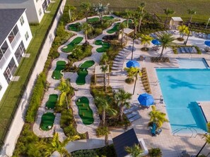 En golfbane med flere putting greens, en swimmingpool og loungeområder med parasoller.
