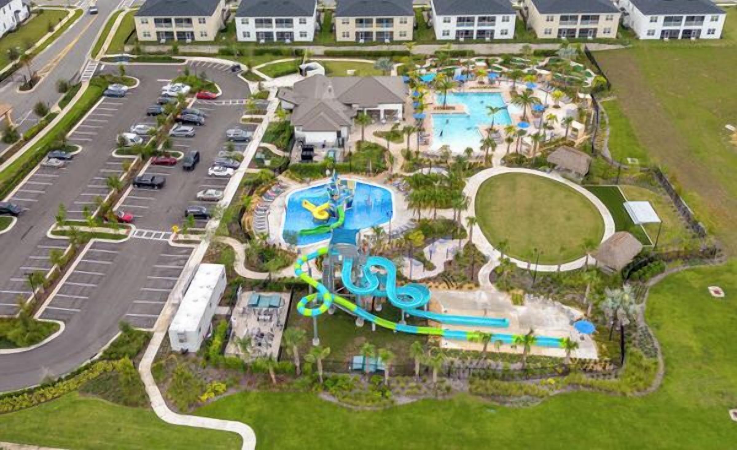 Vista aérea de um resort com piscina, toboáguas e estacionamento.