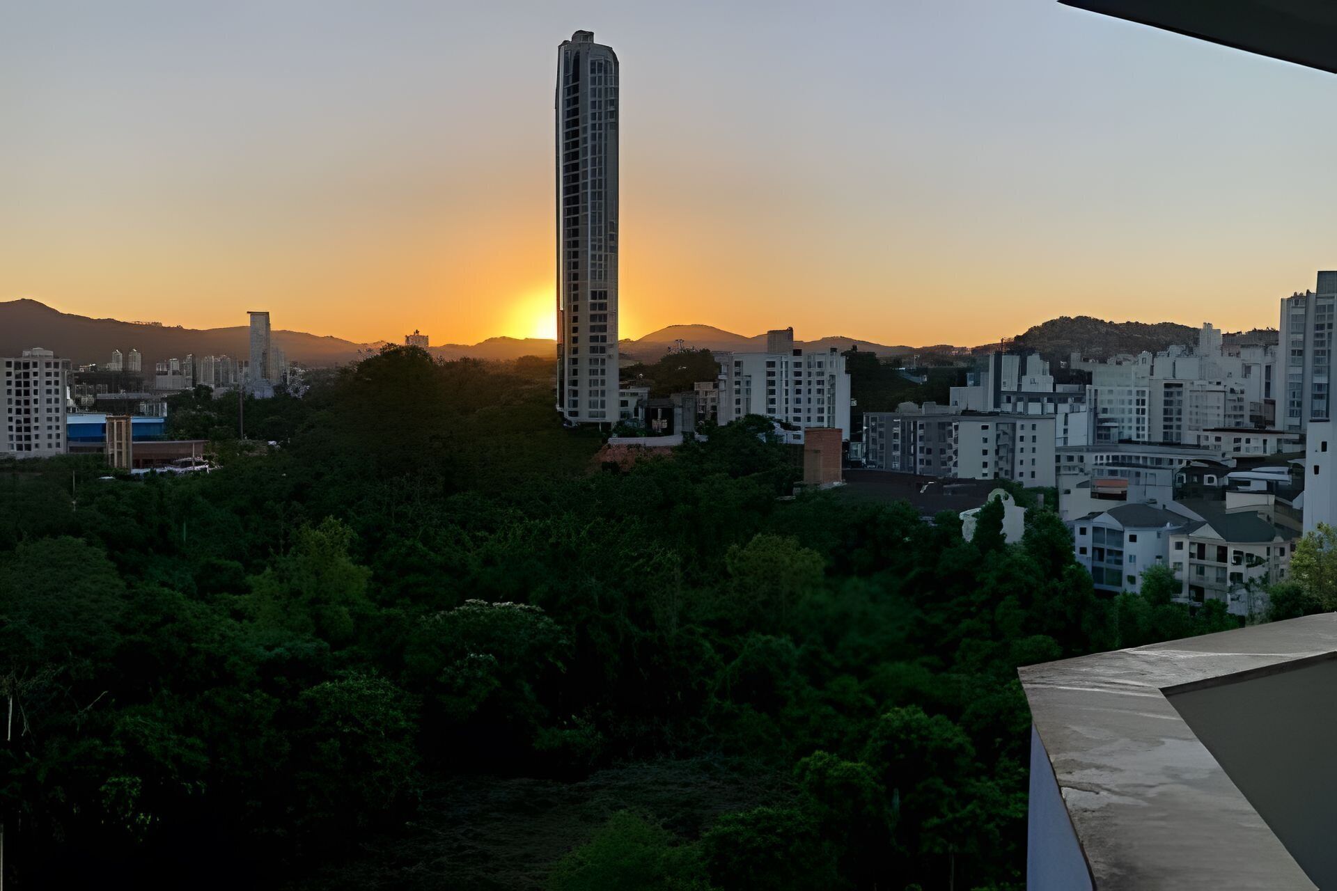 Un paisaje urbano al atardecer con un rascacielos destacado y edificios residenciales.