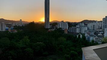 Un paisaje urbano al atardecer con un rascacielos destacado y edificios residenciales.