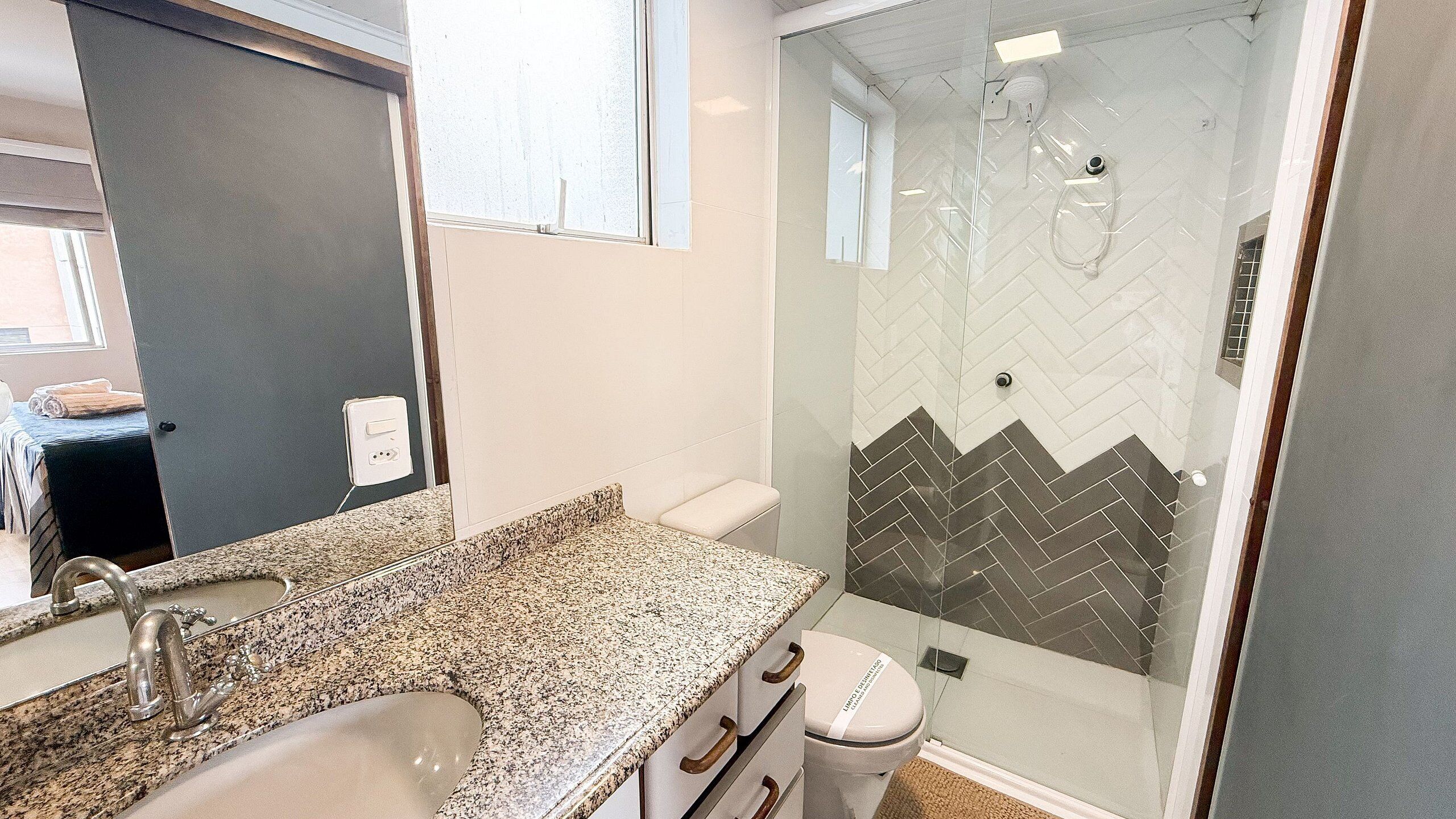 A modern bathroom with a granite countertop, a glass shower enclosure, and a toilet.