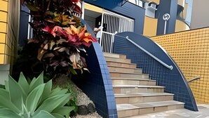 A staircase leading to a building entrance, surrounded by a landscaped area with plants and a small garden bed. - ASA Apartamento Cartagena Oktoberfest (Blumenau)