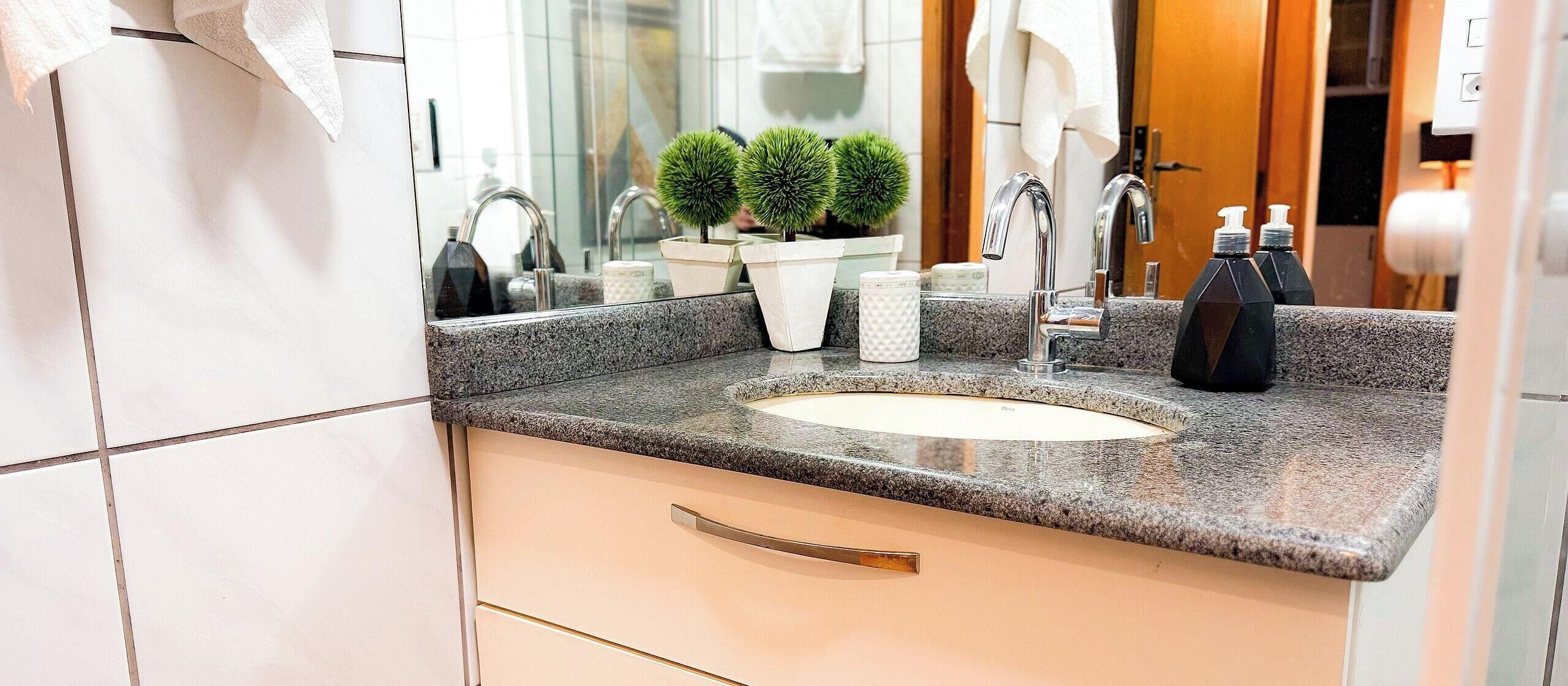 A bathroom with a granite countertop, a sink, a mirror, and a towel rack.