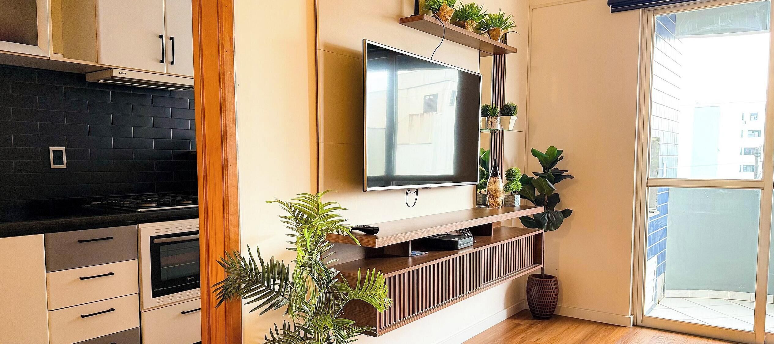 A modern kitchen with a built-in stove, cabinets, and a TV mounted on the wall.