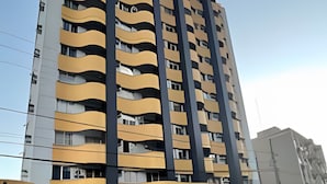 A multi-story building with balconies, a garage, and a street in front. - ASA Apartamento Cartagena Oktoberfest (Blumenau)