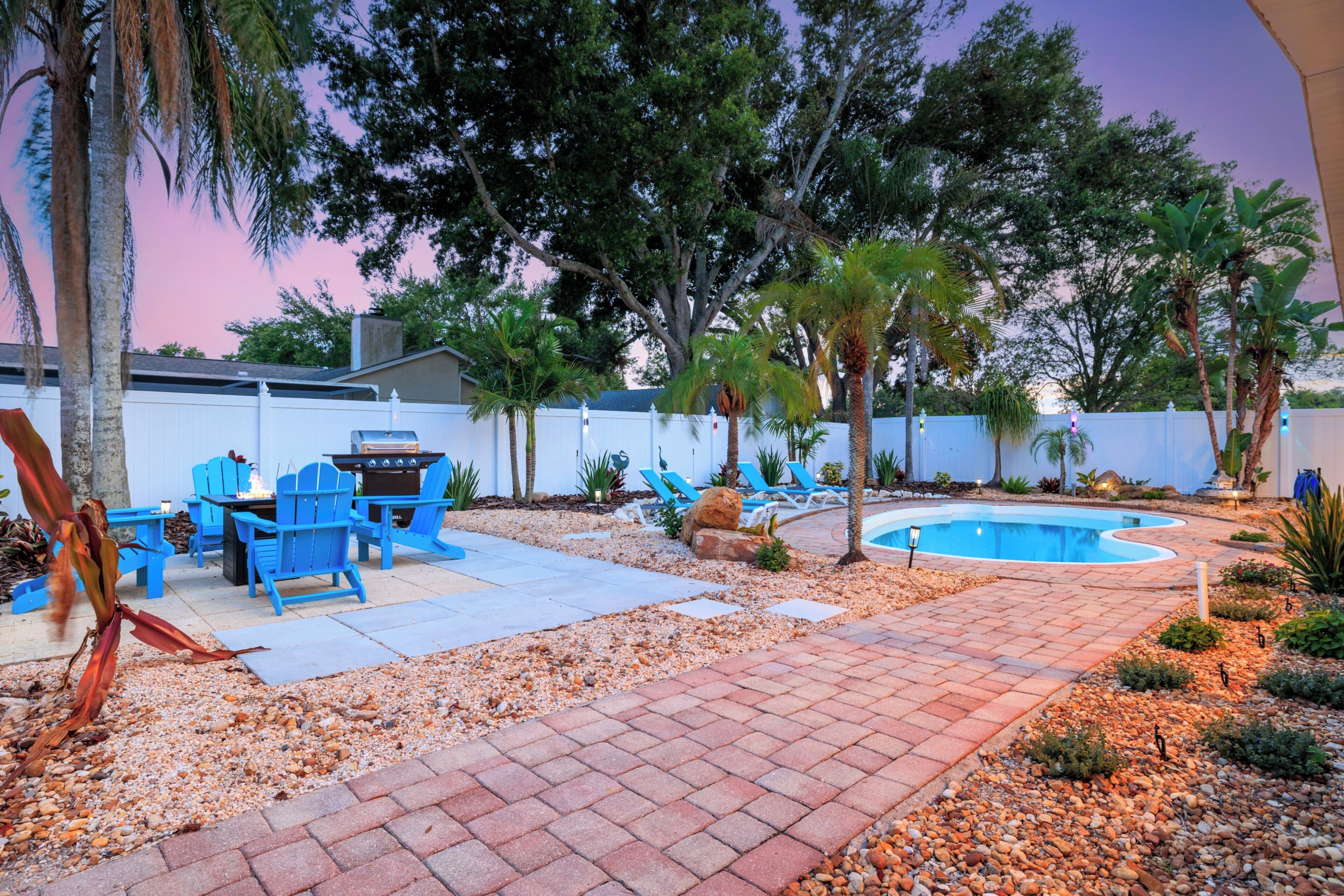 A backyard with a barbecue area, pool, and seating.