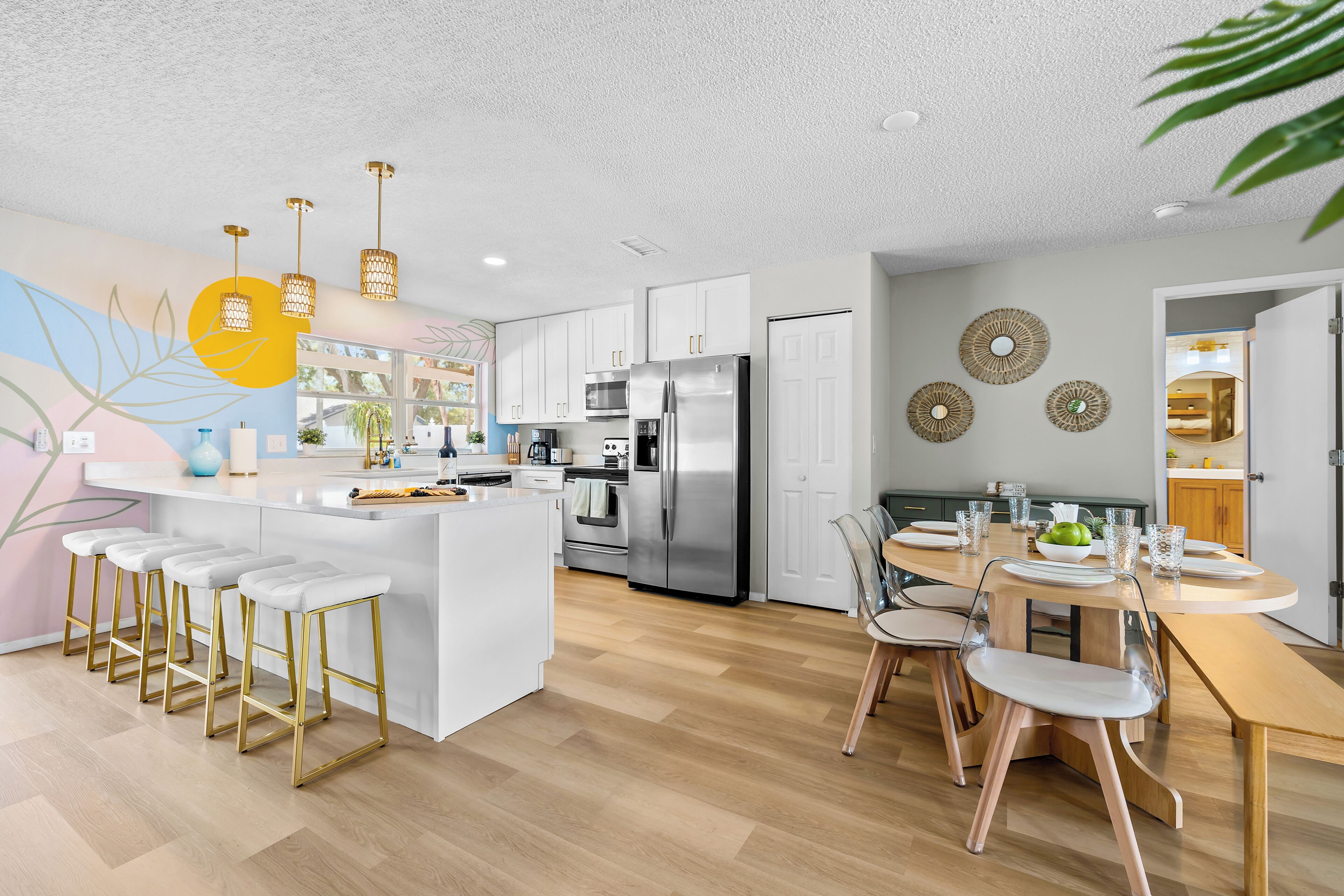 A modern kitchen with white cabinetry, stainless steel appliances, and a central island with bar stools.